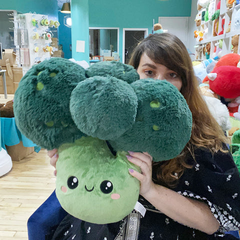 A woman holds the plush broccoli. It is about the size of her torso.