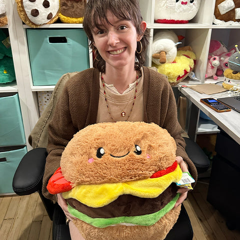 Image shows a woman holding the stuffed cheeseburger. It is almost the size of her torso.