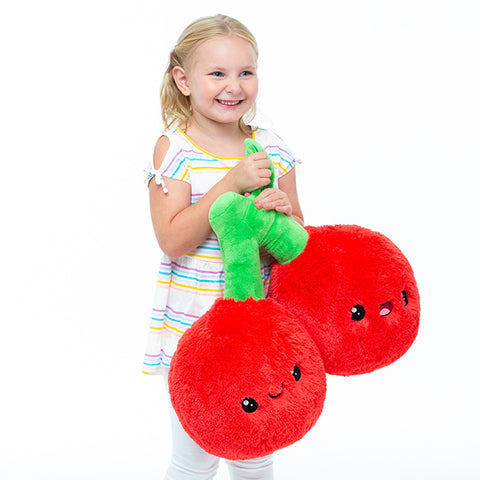 A young girl holds the plush cherries.