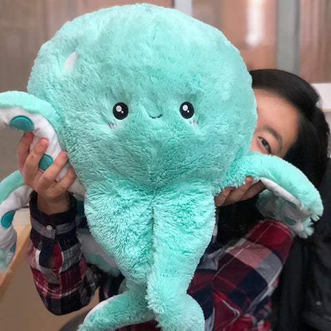 A woman holds up the plush octopus. It is about the size of her torso.