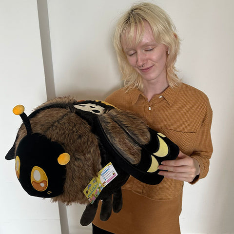 A woman holds the plush Death's Head Hawkmoth. It is about the size of her torso.