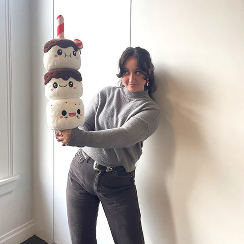 Image shows a woman holding the festive marshmallow stick. It is about as long as her torso.