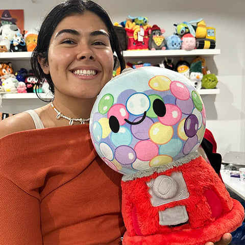 A woman holds the plush gumball machine. It is about the size of her torso.
