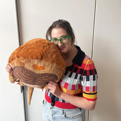 A woman holds the plush horseshoe crab. It is about the size of her torso.