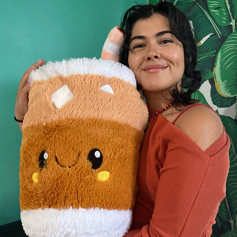 A woman holds the plush iced tea. it is about the size of her torso.