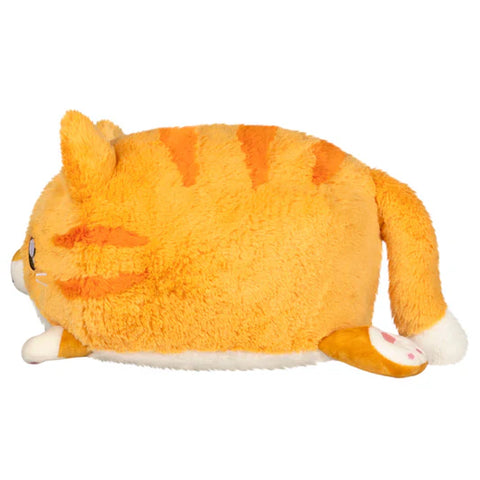 Side view of a Plush toy of an orange cat with white paws on a white background. Its body is round.