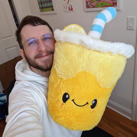 A man holds up the plush lemonade. It is about the size of his torso.