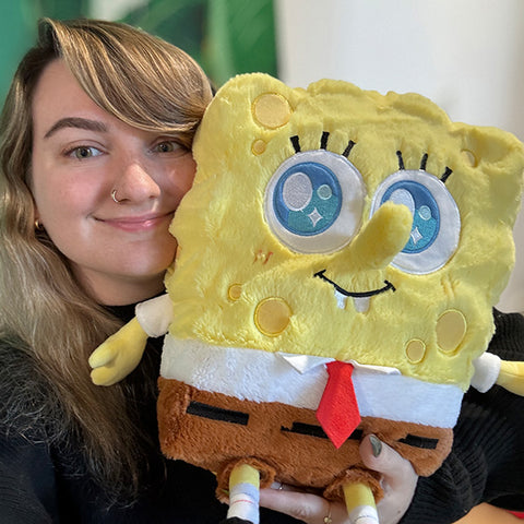 Image shows a woman holding the stuffed Spongebob up to her face. It is much larger than her head.