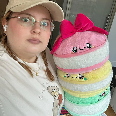 Image shows a woman holding the stuffed macarons. They are approximately the size of her torso.