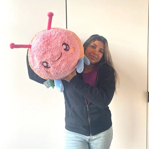 Image shows a woman holding the stuffed caterpillar. It is very large.