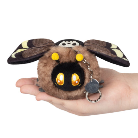 A plush Death's Head Hawkmoth attached to a silver clip keychain, held in someone's hand