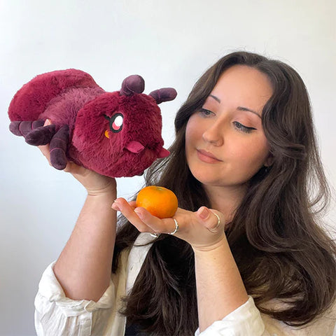 A woman holds the stuffed ant. It is approximately the size of her head.