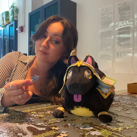 Image shows a woman leaning towards the stuffed Anubis. It is slightly larger than her head.