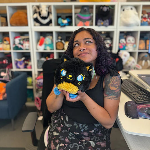 Image shows a woman holding the stuffed Bastet. It is slightly larger than her head.