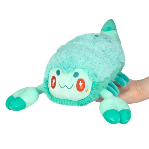 Light teal plush scorpion held by a hand on a white background