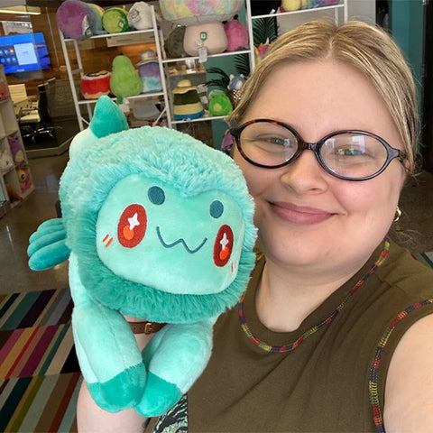 A woman holding the plush scorpion toy. It is slightly larger than her head.