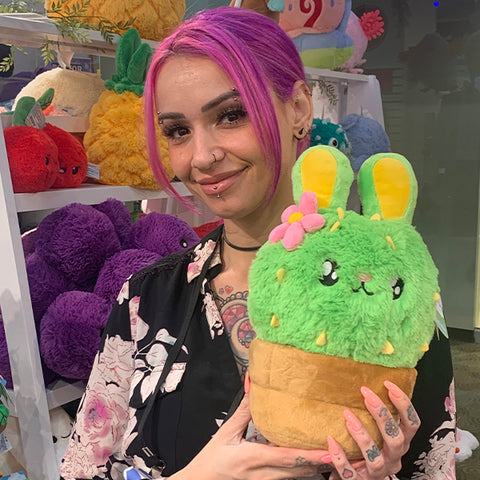 Image shows a woman holding the stuffed bunny cactus. It is slightly larger than her head.