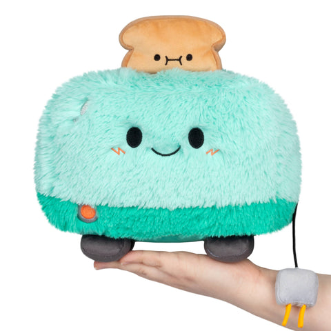 Plush toy resembling a toaster with a smiling face on a white background