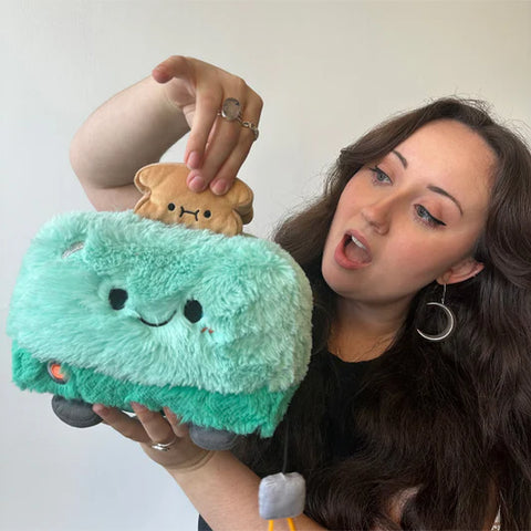 A woman holds the plush toaster near her face. It is slightly larger than her head.