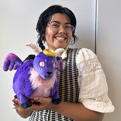 Image shows a woman holding the stuffed cosmic demon. It is slightly larger than her head.