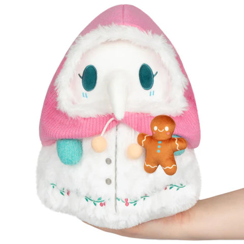 Image shows a stuffed plague nurse with a fuzzy pink bonnet, holding a stuffed gingerbread man.