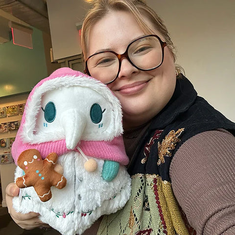 Image shows a woman holding the stuffed plague nurse. It is slightly larger than her head.