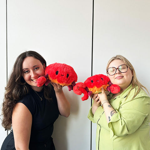 Image shows two women holding the stuffed crabs. They are approximately the size of their faces.