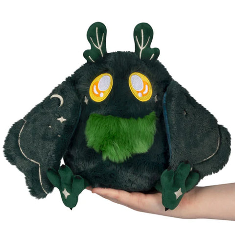 A forest-themed baby mothman plush. He is dark green with yellow eyes and a green beard