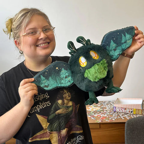 A woman holds the stuffed mothman. His body is about the size of her head.
