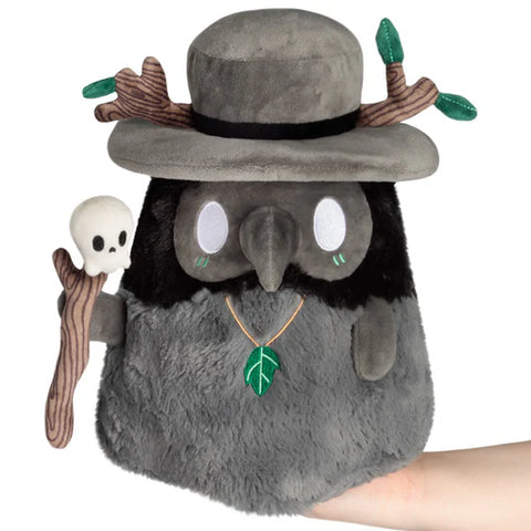 Image shows a druid themed plague doctor. He is black and grey, carries a stick with a skull on top, and has sticks in his hat.