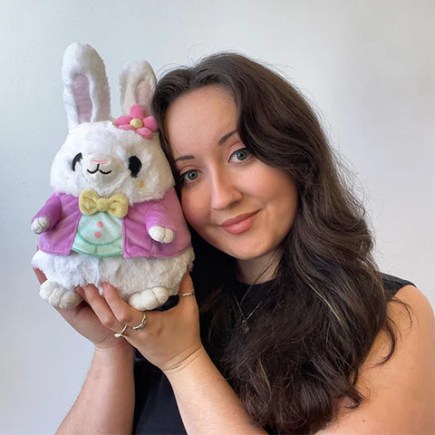 Image shows a woman holding the stuffed easter bunny up to her face. It is approximately the size of her head.