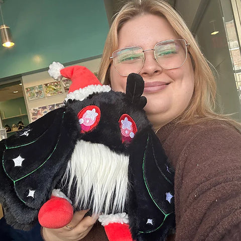 Image shows a woman holding the festive baby mothman. He is slightly larger than her head.