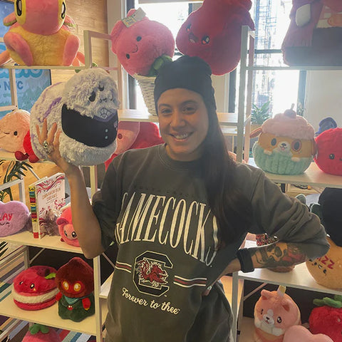 Image shows a woman holding the stuffed goth worm. It is slightly larger than her head.