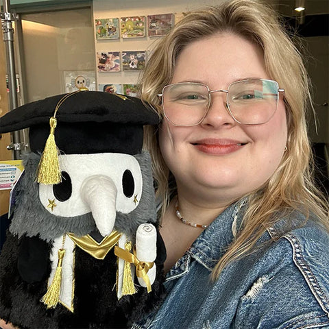 Image shows a woman holding the graduation plague doctor. It is slightly larger than her head.