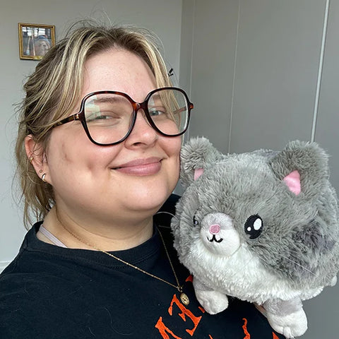 Image shows a woman holding the stuffed grey kitty. It is approximately the size of her head.