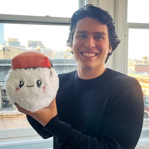 Image shows a man holding the stuffed ham musubi sushi. It is approximately the size of his head.