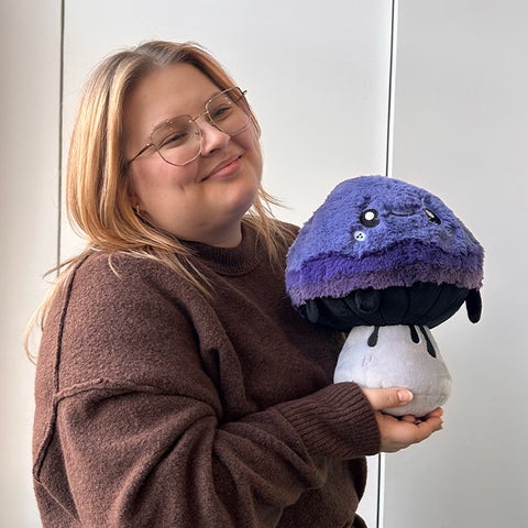 Image shows a woman holding the stuffed inky cap mushroom. It is slightly larger than her head.
