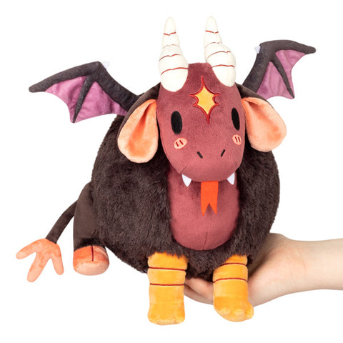 A creature with a brown body, red face and belly, yellow legs, wings, and horns held in someone's hand