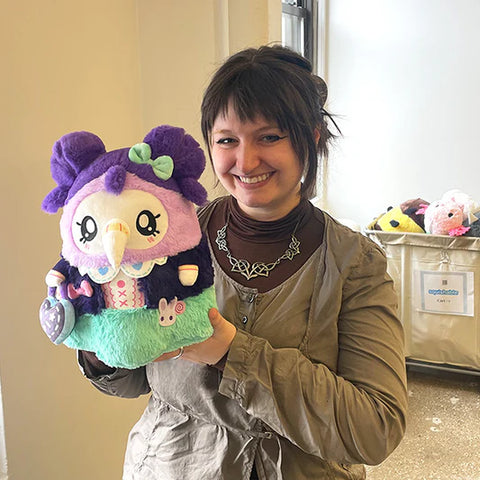 Image shows a woman holding the stuffed Kawaii-themed plague nurse, it is slightly larger than her head