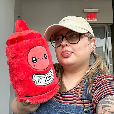 Image shows a woman holding the stuffed ketchup bottle. It is larger than her head.