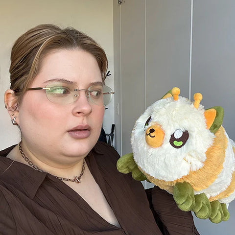 Image shows a woman holding the stuffed kittypillar. It is approximately as wide as her face.