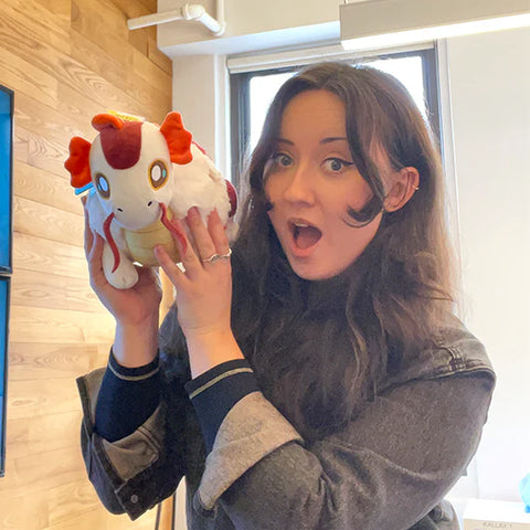 Image shows a woman holding the stuffed koi fish dragon up to her face. It is approximately the size of her head.