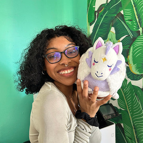 A woman holds the plush lunar dragon near her face. It is slightly larger than her head.