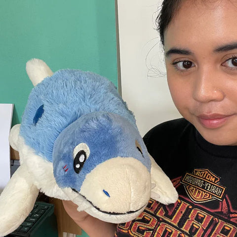 Image shows a woman holding the stuffed Mosasaurus. It is slightly larger than her head.