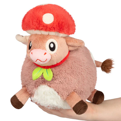 Image shows a stuffed brown cow wearing a red mushroom hat