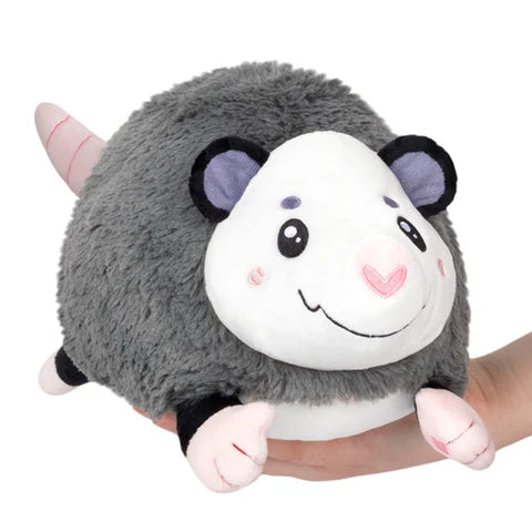 Image shows a hand holding a round stuffed opossum