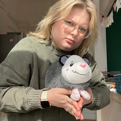 Image shows a woman holding the stuffed opossum. It is approximately the size of her head.