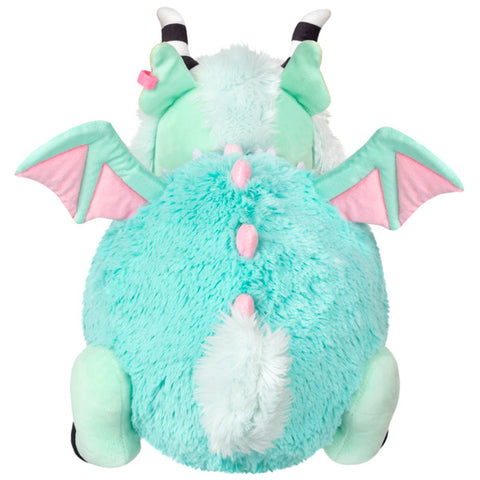A back view of the plush pastel demon. It has pink wings and pink spikes down its back.
