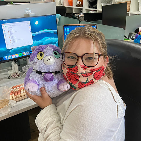 A woman holds the cat near her face. It is slightly larger than her head.