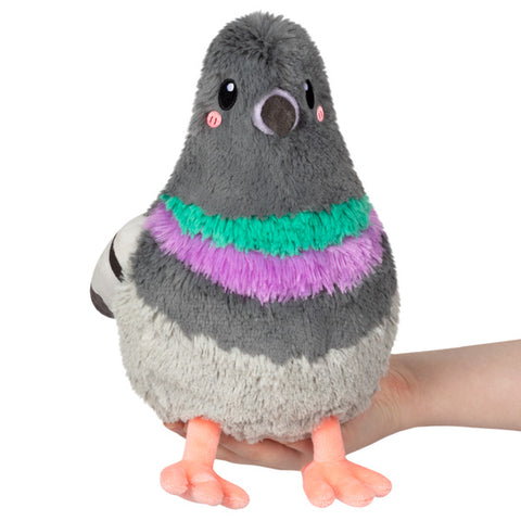 A plush toy resembling a pigeon, held in someone's hand.